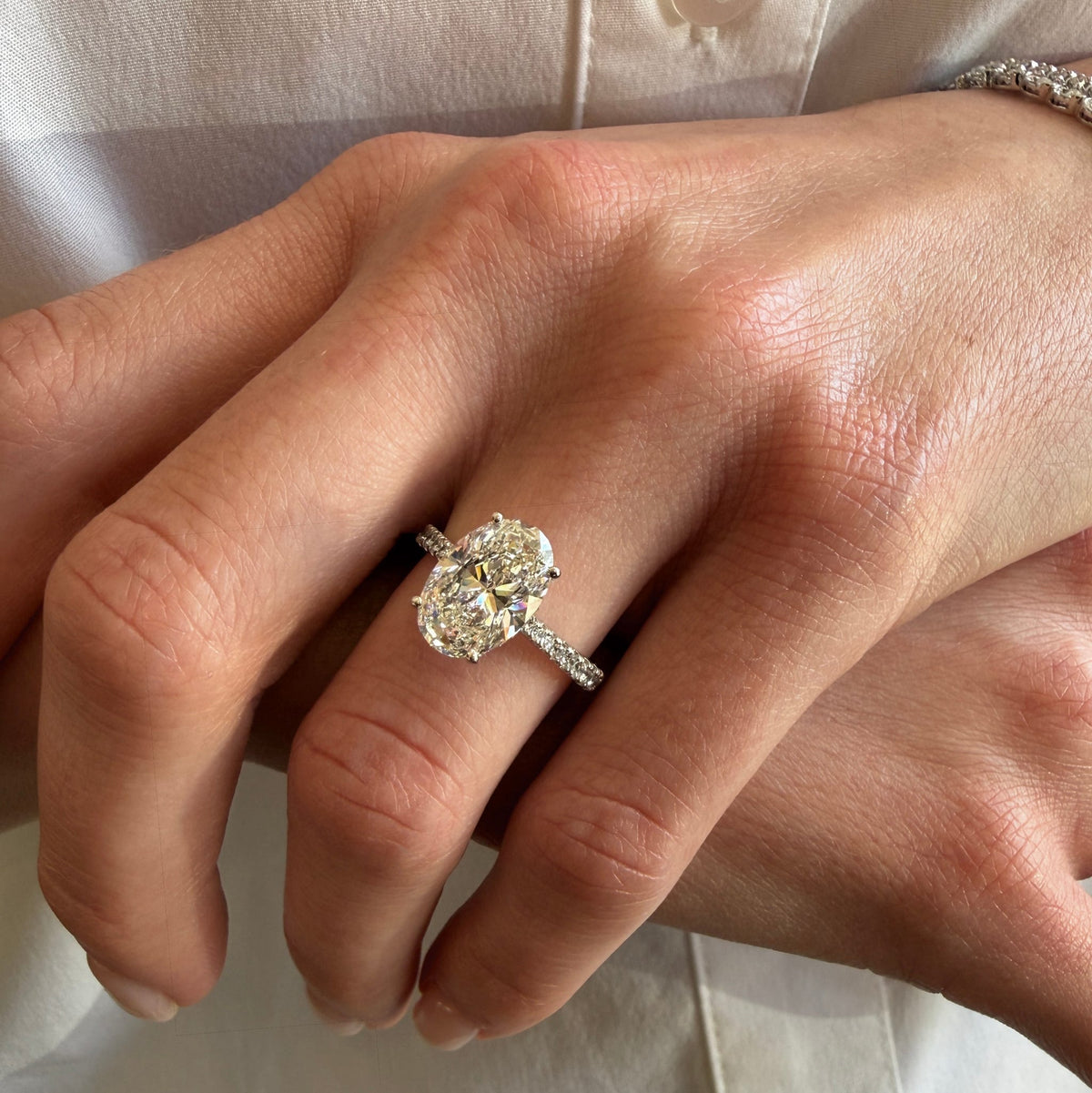 Close-up of a hand wearing a diamond ring on a neutral background