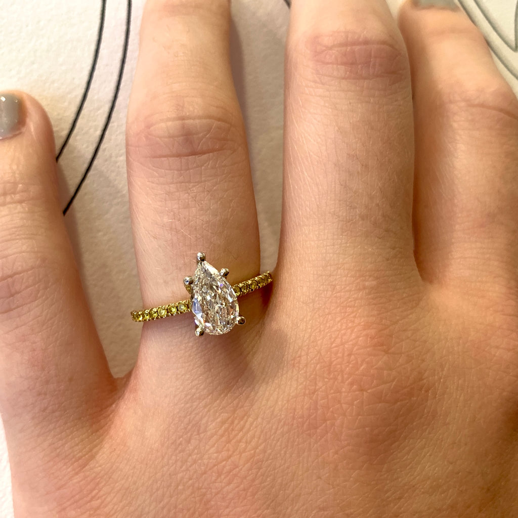 Gold ring with a pear-shaped diamond on a person's finger