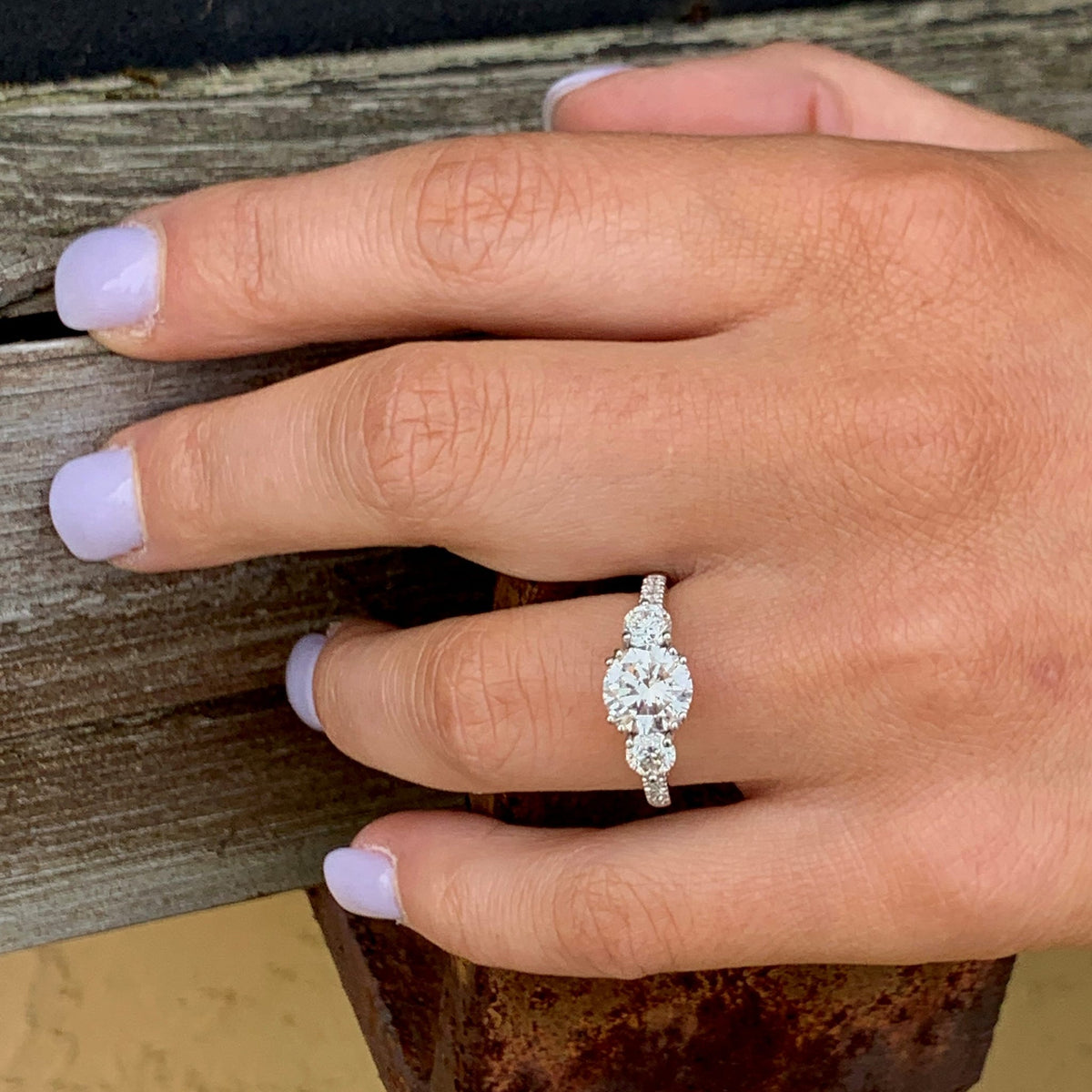 Hand wearing a diamond ring on a wooden surface
