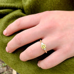Hand wearing a gold ring with a green background