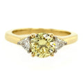 Gold ring with a yellow gemstone and two smaller diamonds on a white background