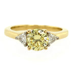 Gold ring with a yellow gemstone and two smaller diamonds on a white background
