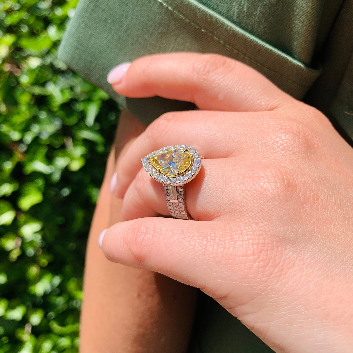 Hand wearing a yellow gemstone ring with a green background