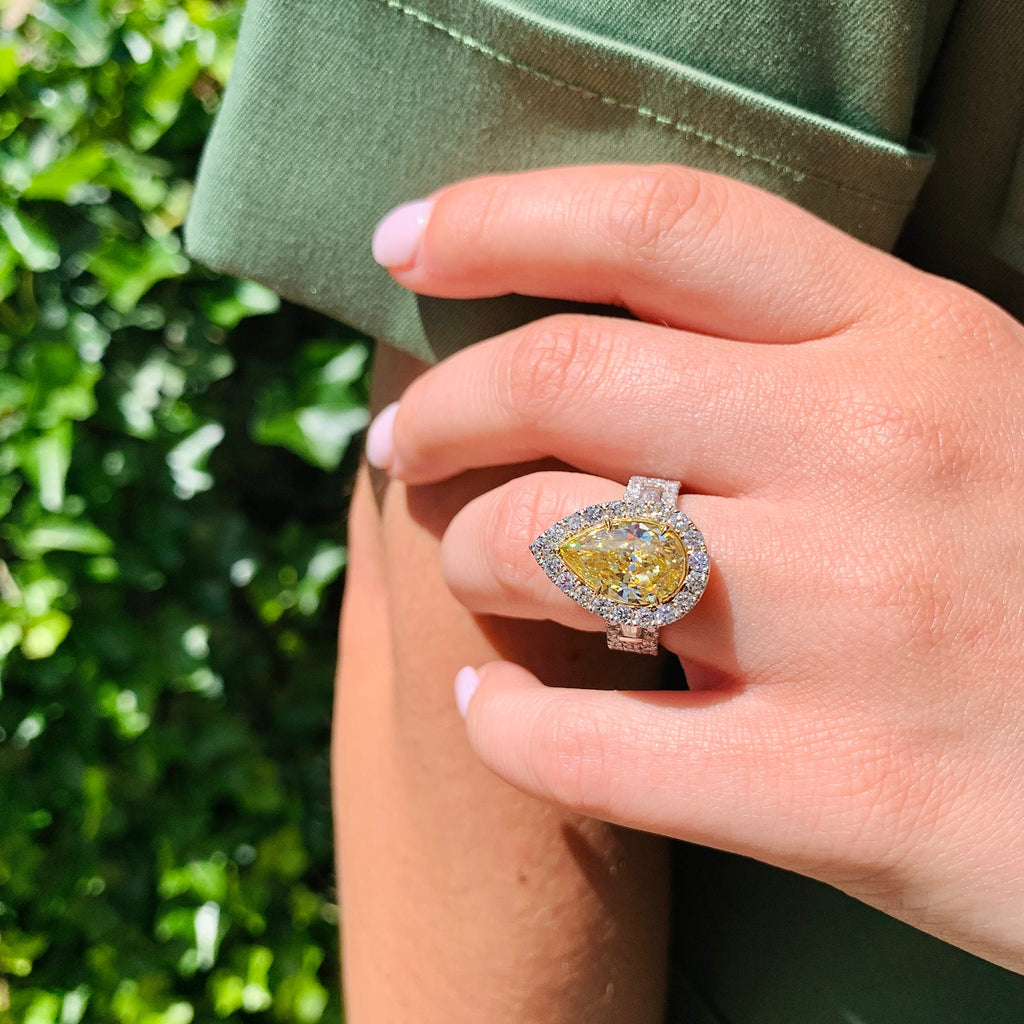 Hand wearing a yellow diamond ring with a green background