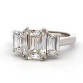 Diamond ring with emerald-cut center stone and baguette side stones on a white background