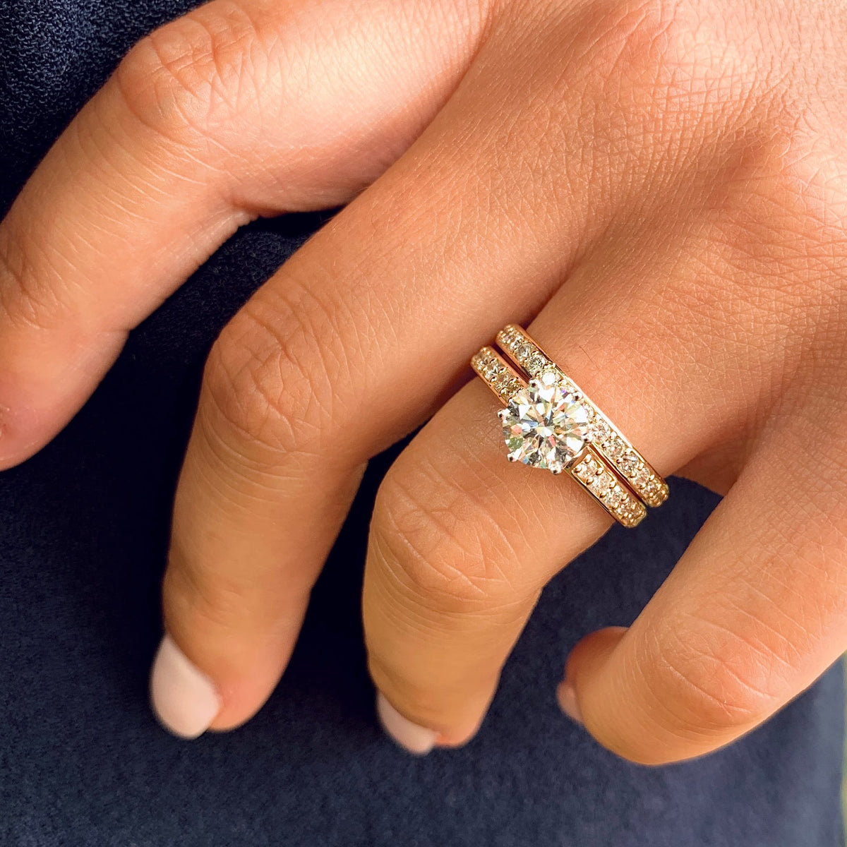 Close-up of a hand wearing two diamond rings on a dark background
