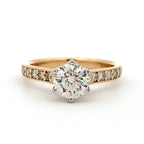 Gold ring with a large diamond and smaller diamonds on the band against a white background