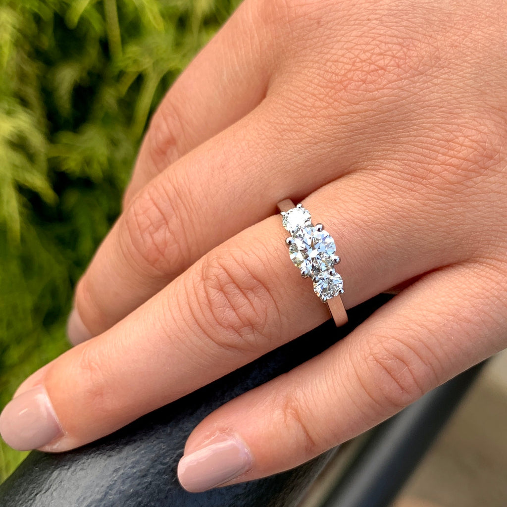 Diamond ring on a finger with a blurred green background