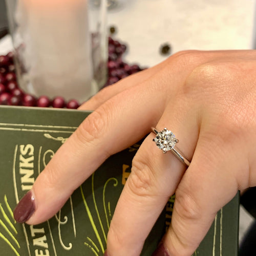 Hand wearing a diamond ring with a blurred background