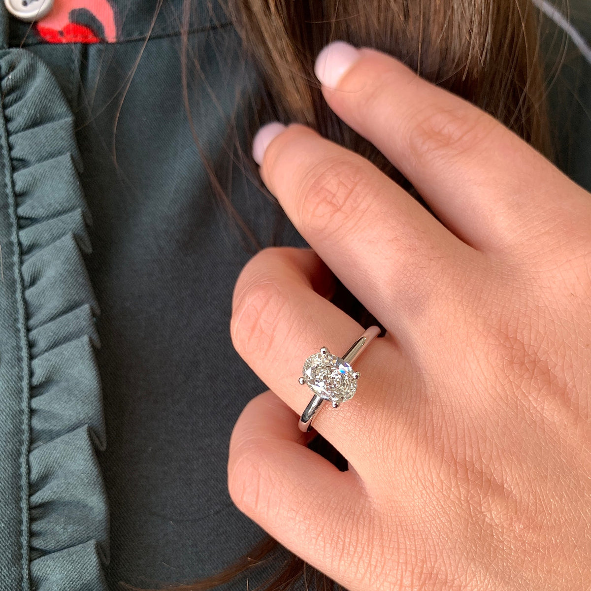 Close-up of a hand wearing a diamond ring with a blurred background