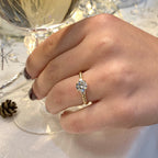 Hand wearing a gold ring with a diamond, next to a glass and decorative items.