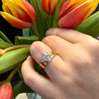 Hand wearing a diamond ring with tulips in the background