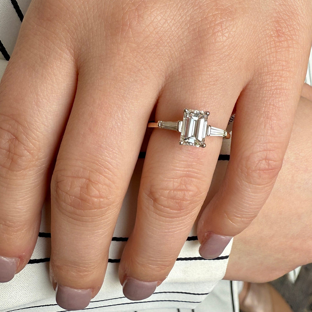 Close-up of a hand wearing a diamond ring on a striped background