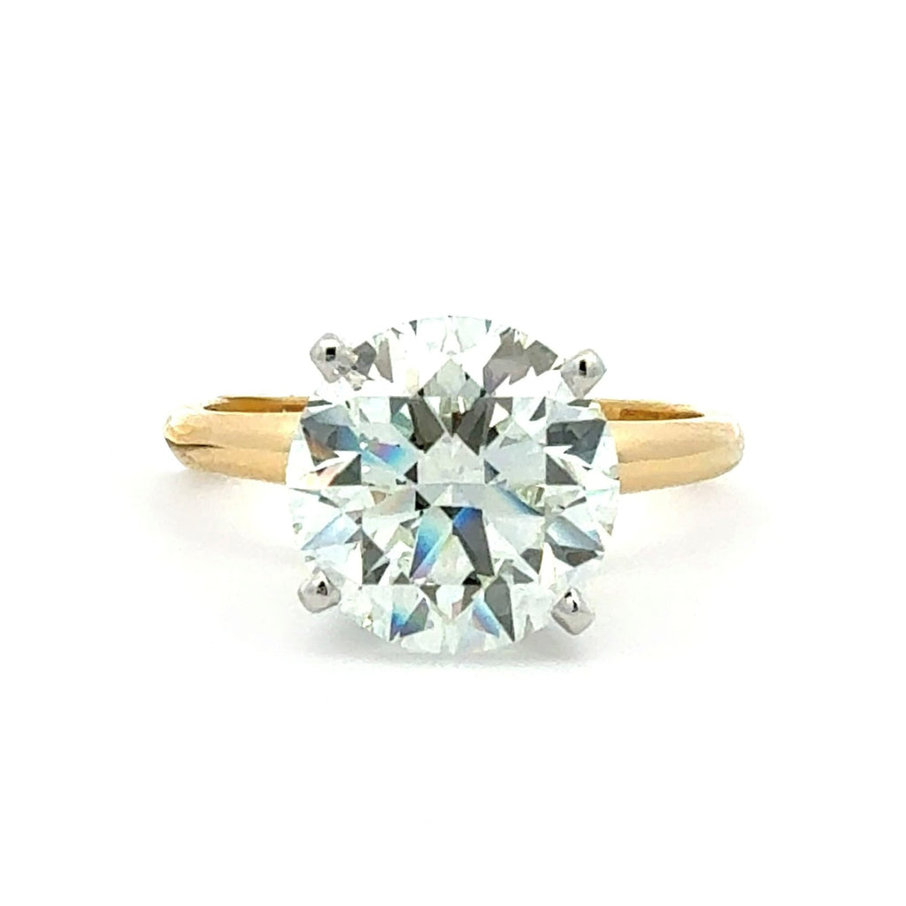 A classic solitaire engagement ring featuring a round brilliant-cut diamond set in a yellow gold band with a silver-colored prong setting, shown on a plain white background.