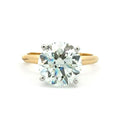 A classic solitaire engagement ring featuring a round brilliant-cut diamond set in a yellow gold band with a silver-colored prong setting, shown on a plain white background.