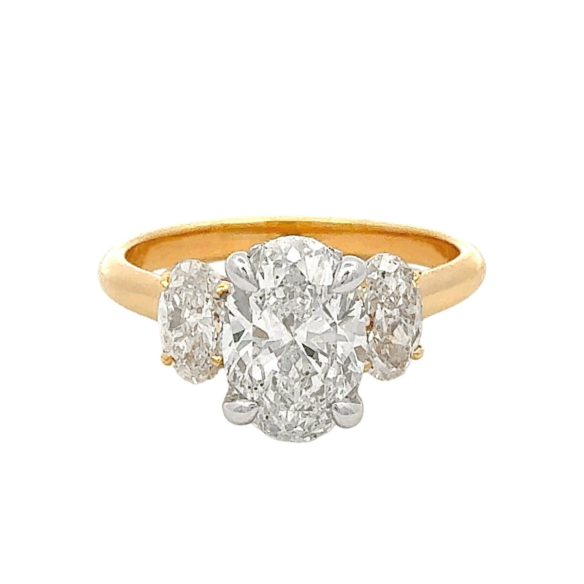 Gold ring with a large diamond and two smaller diamonds on a white background