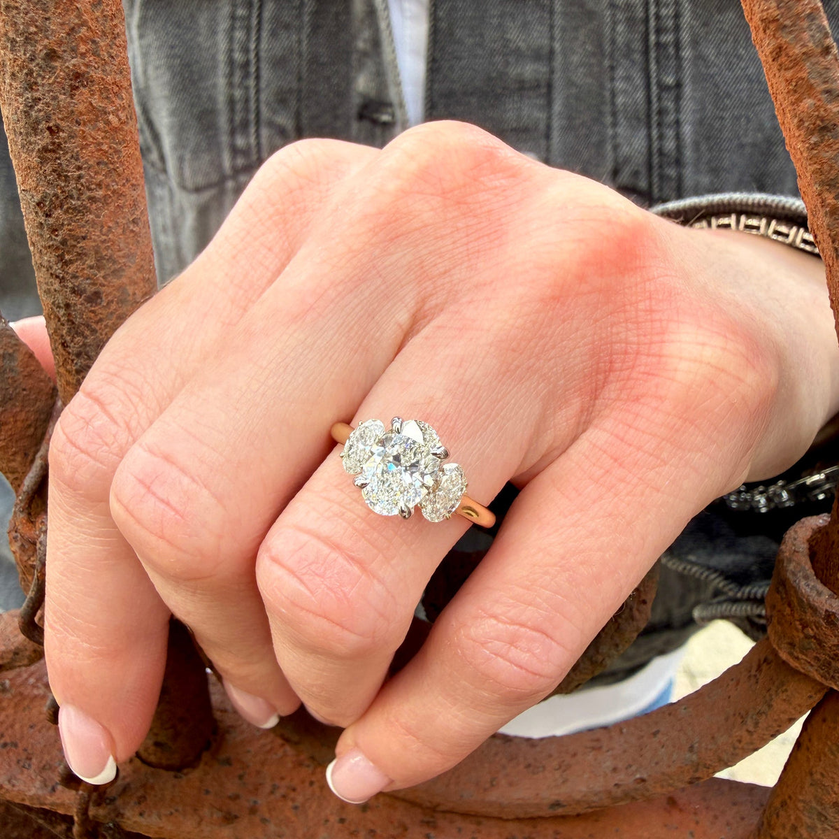 Hand wearing a diamond ring on a rusty metal surface