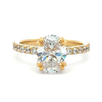 A yellow gold engagement ring featuring a large oval-cut center diamond and a pavé band with small accent diamonds, set against a plain white background.