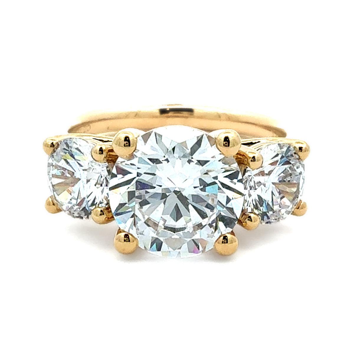 A yellow gold three-stone diamond ring with a large round center diamond and two round side diamonds, set against a plain white background.