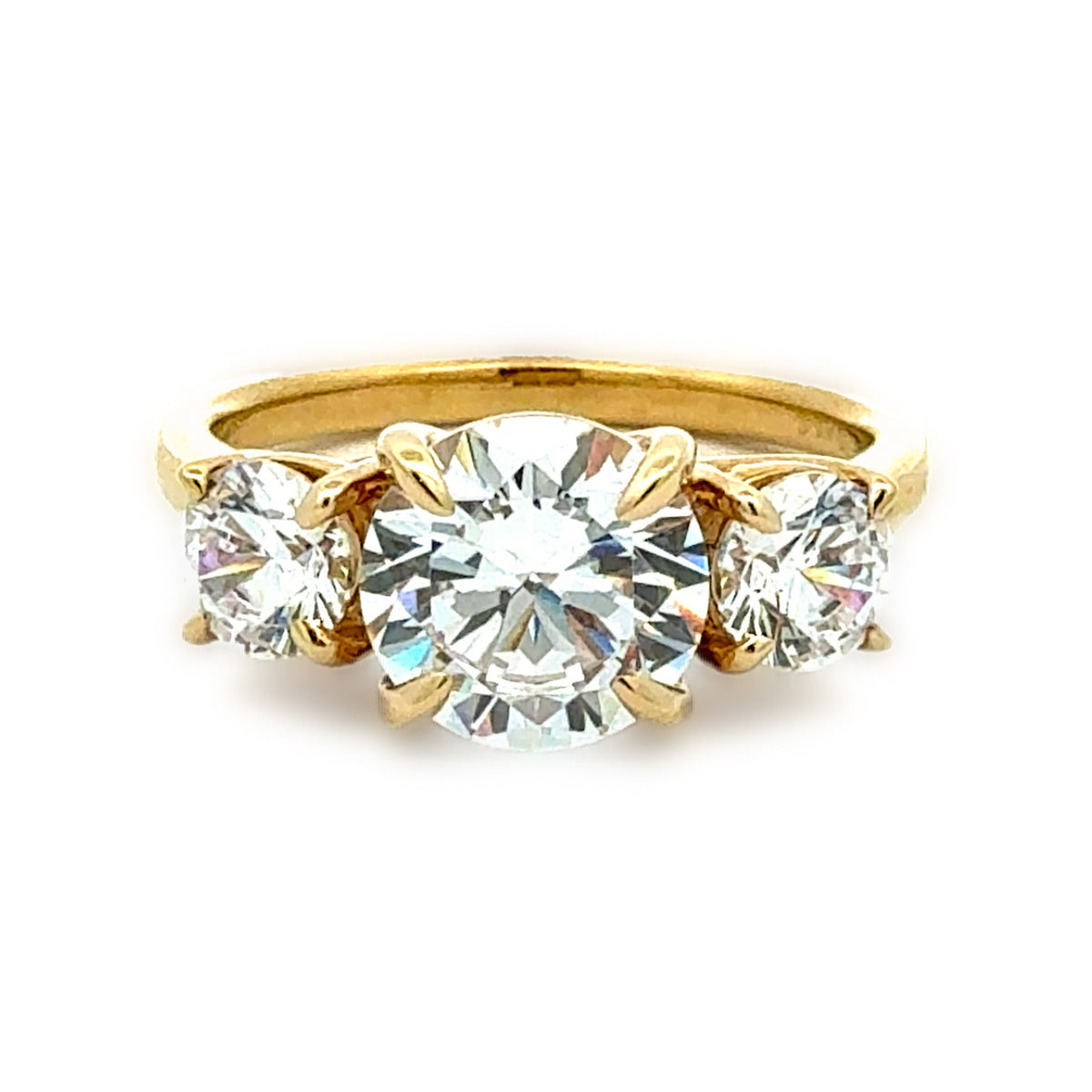 A yellow gold three-stone ring featuring a large round brilliant-cut center diamond flanked by two smaller round diamonds, set against a plain white background.