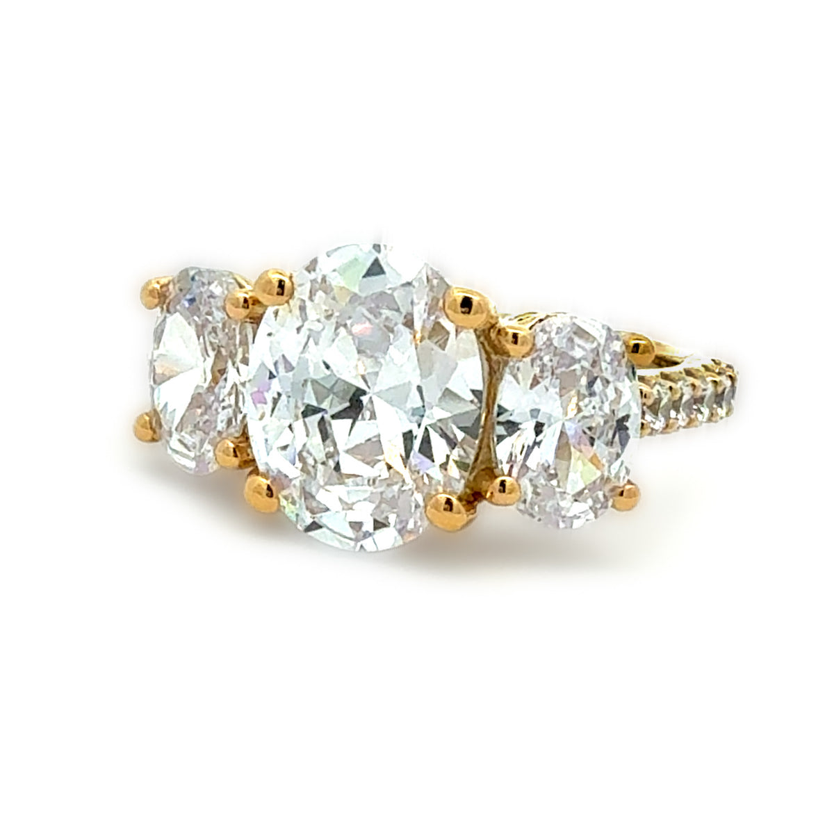 A yellow gold three-stone diamond ring featuring a large oval center diamond flanked by two smaller round diamonds, with a pavé-set diamond band, shown on a white background.