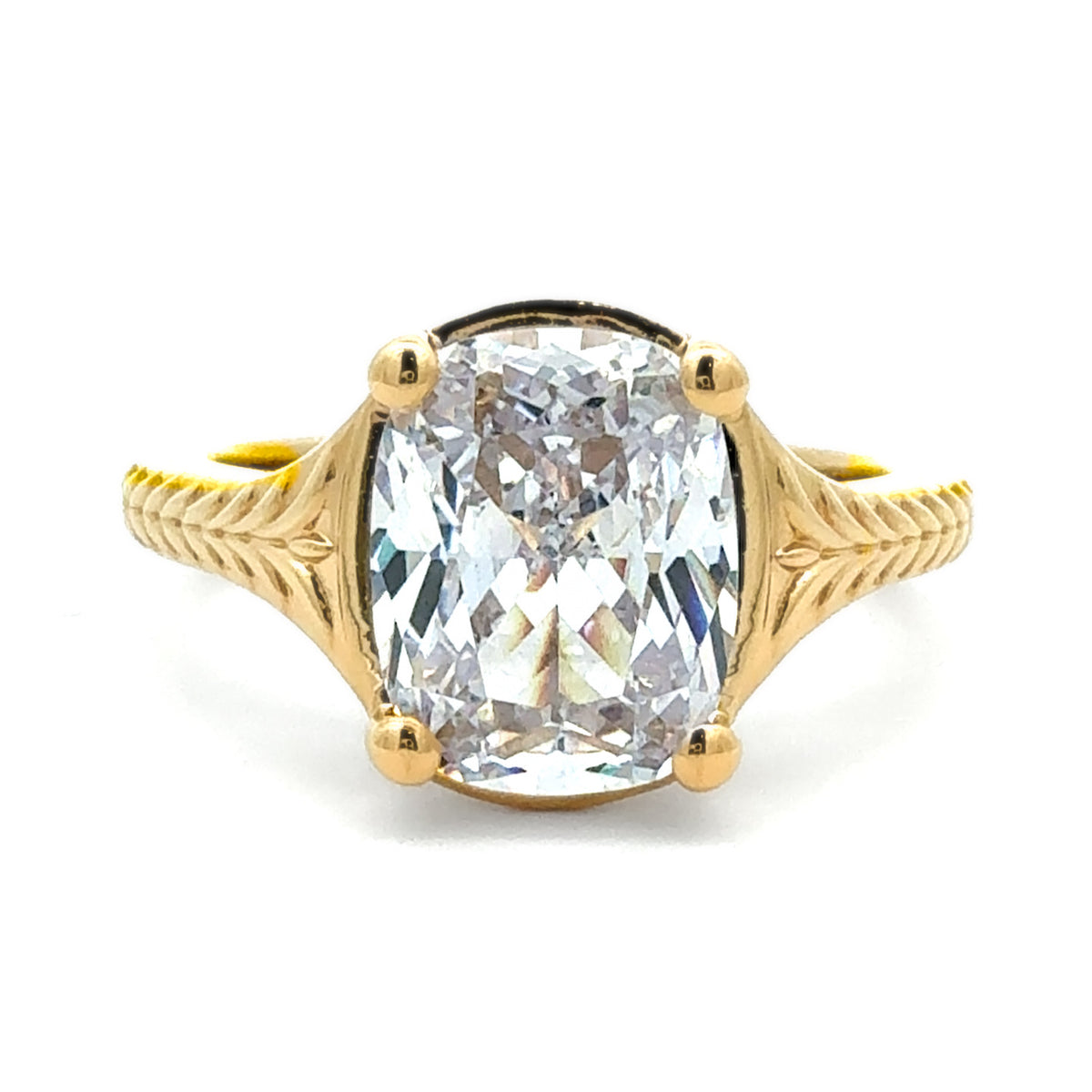 A yellow gold ring featuring a large cushion-cut clear gemstone in a four-prong setting, with decorative split shanks, shown on a plain white background.