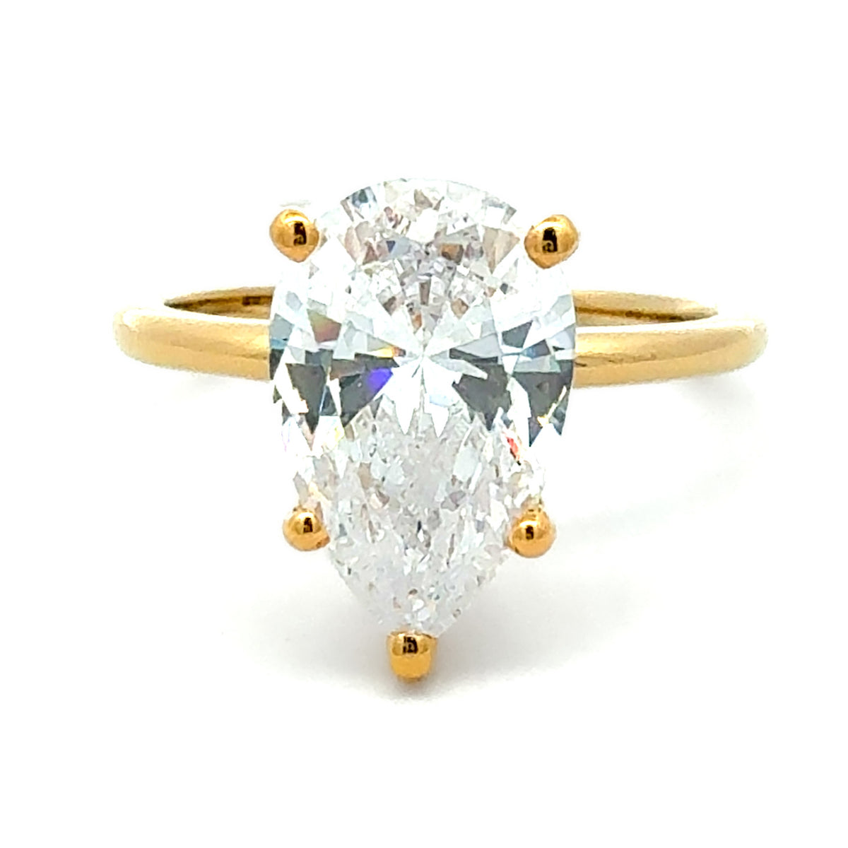 A pear-cut diamond ring set in a yellow gold band with four-prong settings, shown against a plain white background.