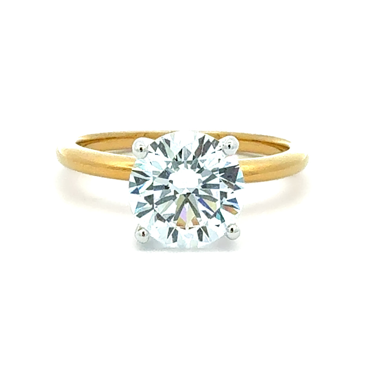A classic solitaire engagement ring featuring a round brilliant-cut diamond set in a four-prong white metal setting on a polished yellow gold band, shown against a plain white background.