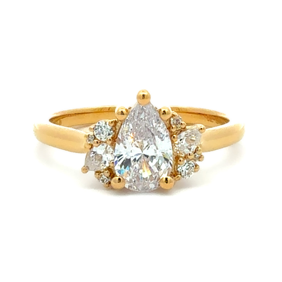 A yellow gold ring featuring a pear-cut diamond center stone flanked by smaller round diamonds, set on a plain white background.