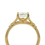 A yellow gold solitaire engagement ring with a round brilliant-cut clear gemstone, shown against a plain white background.