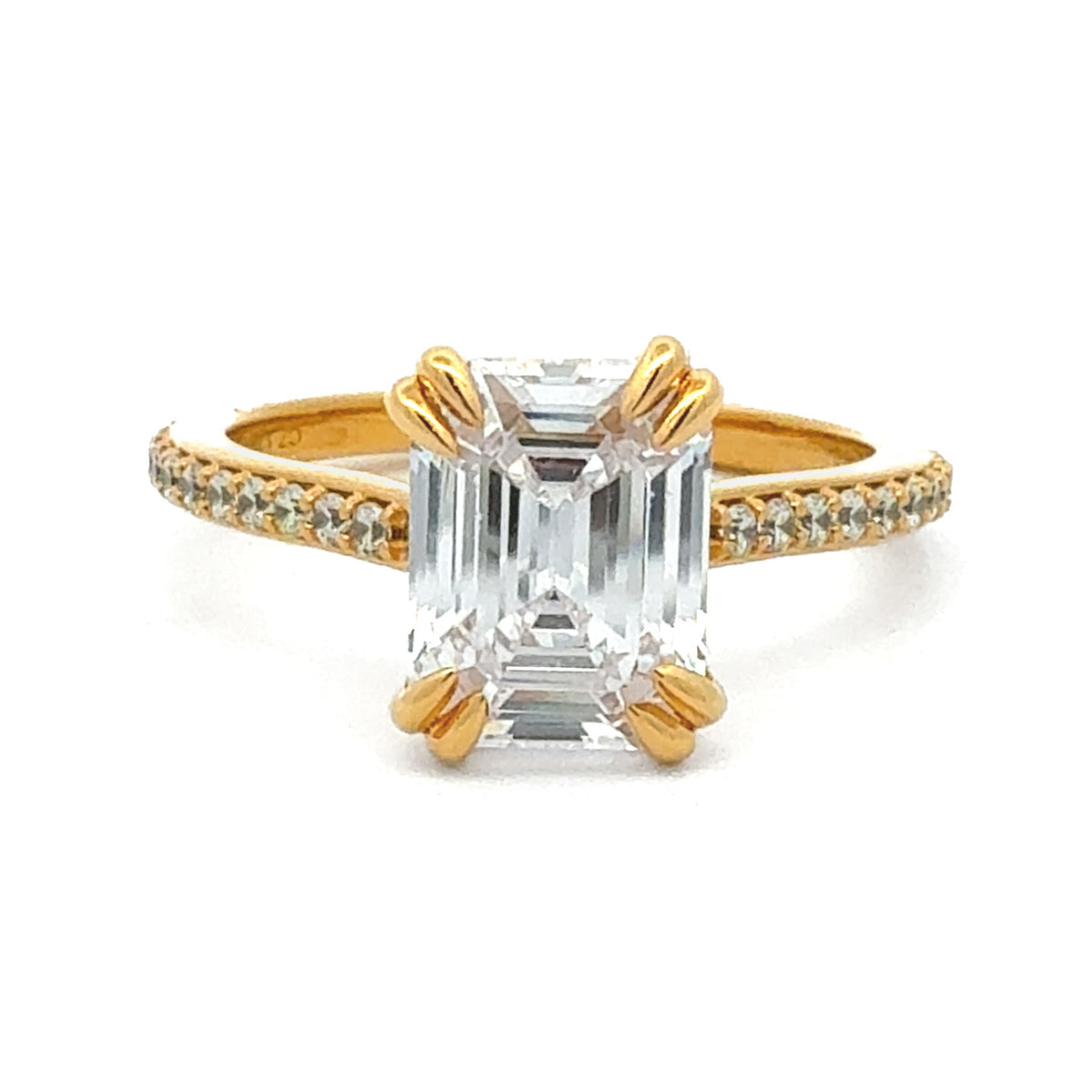 A yellow gold ring featuring a large emerald-cut clear center stone and small pavé-set diamonds along the band, shown on a plain white background.