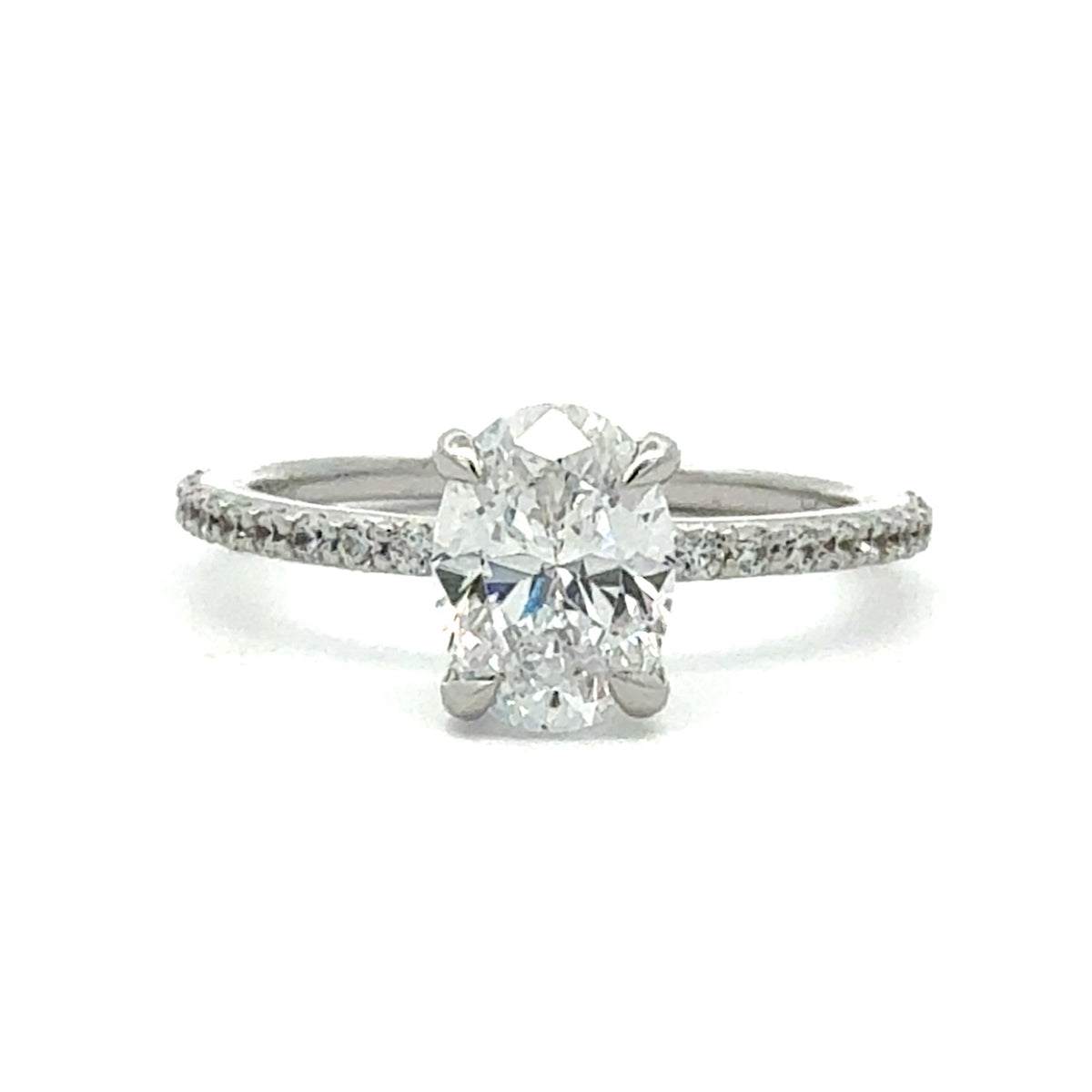 A silver-toned diamond engagement ring featuring a large round brilliant-cut center stone in a four-prong setting, with a pavé band set with small diamonds, shown on a plain white background.