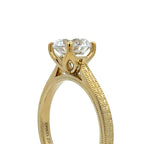 A close-up shot of a yellow gold solitaire engagement ring with a round brilliant-cut clear gemstone, set against a plain white background.
