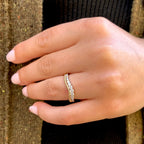 Close-up of a hand wearing two gold rings on a textured surface