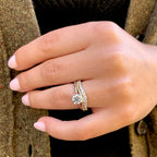Close-up of a hand wearing two diamond rings on a textured surface