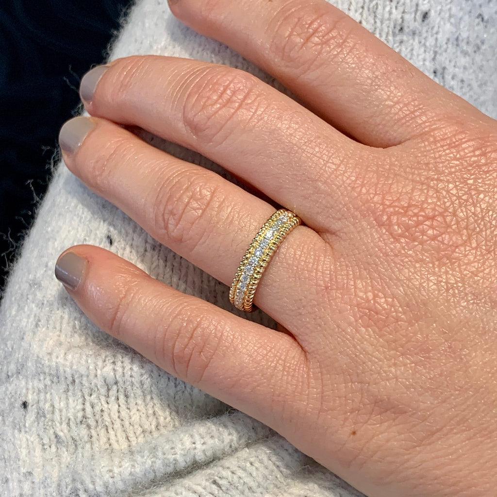 Close-up of a hand wearing a gold ring on a textured surface