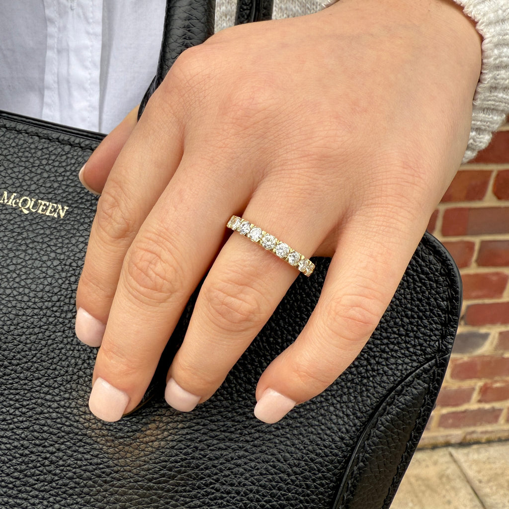 Hand wearing a diamond ring on a black handbag with 'McQueen' branding.