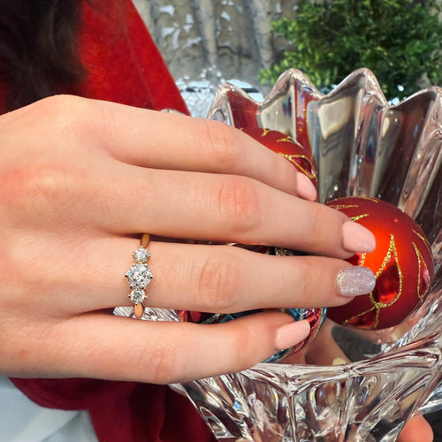 Hand wearing a diamond ring with a decorative background