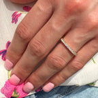 Close-up of a hand wearing a diamond ring with a colorful background