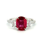 Ring with a red gemstone and two smaller clear stones on a white background