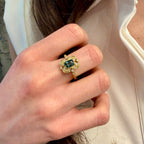 Close-up of a hand wearing a gold ring with a blue gemstone.