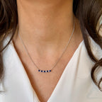 Necklace with blue stones worn by a person against a neutral background