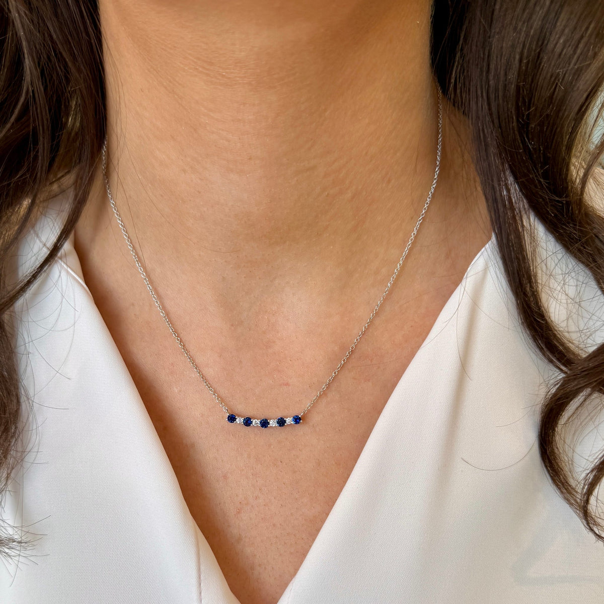 Necklace with blue stones worn by a person against a neutral background