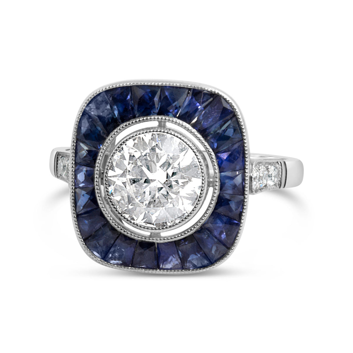 A vintage-style square ring featuring a large round brilliant-cut diamond in the center, surrounded by a halo of deep blue sapphires, with a silver-toned band accented by small side diamonds.