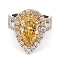 Ring with a yellow pear-shaped diamond and diamond halo on a white background