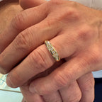 Close-up of a hand wearing a gold ring with diamonds.