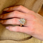 Hand wearing a diamond ring on a beige fabric background