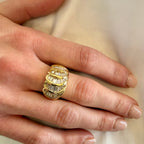 Gold ring with diamond accents on a hand against a neutral background