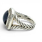 A sterling silver David Yvon ring featuring a twisted cable band, a bezel-set oval dark blue sapphire, and small pavé-set clear accent stones, shown on a white background.