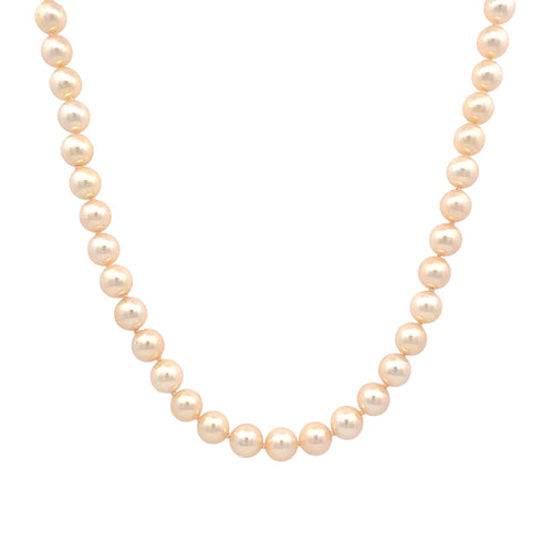 A strand of round, cream-colored freshwater pearls arranged in a curved necklace shape against a solid white background.
